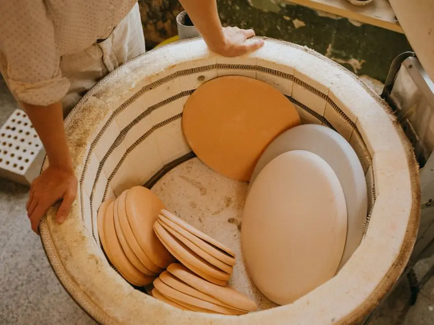 Hands stacking bisque plates inside a kiln