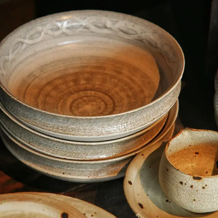 Stacked speckled stoneware bowls and plates with warm amber glaze